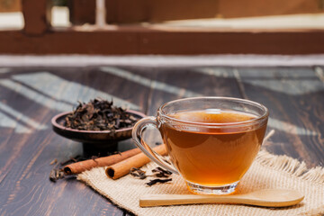 Close-up shot of a cup of hot tea or coffee placed on a desk or a table, drinking coffee by the window at work or at home, at sunset or in the morning.