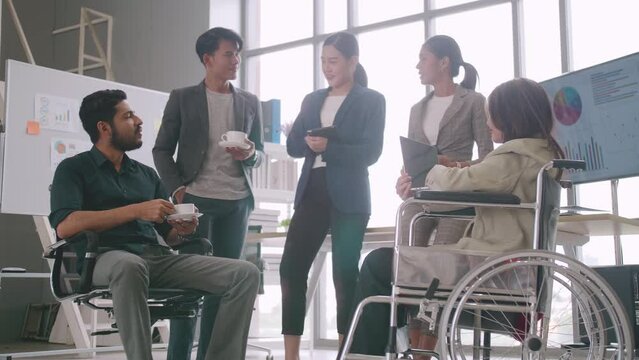 A disabled company employee is able to work happily with colleagues in the office.