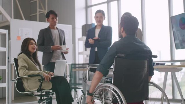 A disabled company employee is able to work happily with colleagues in the office.