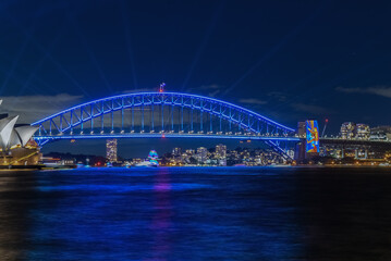 Colourful Light show at night on Sydney Harbour NSW Australia. The bridge illuminated with lasers and neon coloured lights. Sydney laser light show