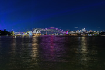 Obraz premium Colourful Light show at night on Sydney Harbour NSW Australia. The bridge illuminated with lasers and neon coloured lights. Sydney laser light show