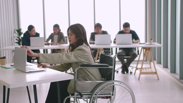 A disabled company employee is able to work happily with colleagues in the office.