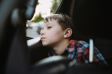 Sad bored caucasian boy travelling by car sitting by open window