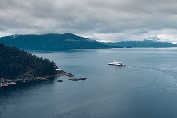 Dramatic view of the sea with the vessel, mountains, and the clouds in the background.