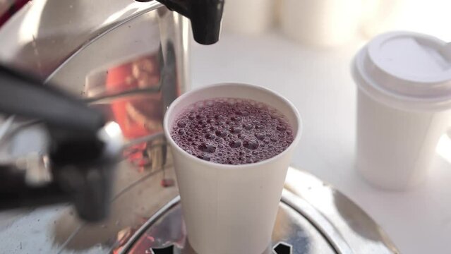 Man hand pouring fresh fruit juice or punch from drinking tank machine at party.