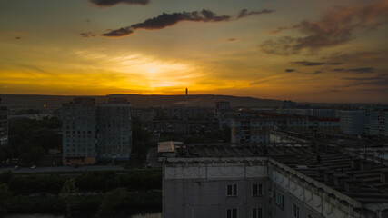 Dramatic sunset landscape with puffy clouds lit by orange setting sun and blue sky