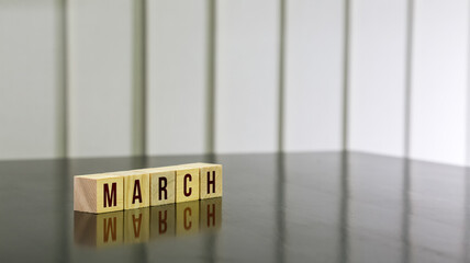 MARCH word on wooden cube on black gloss wooden table. Selected focus