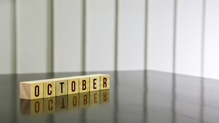 OCTOBER word on wooden cube on black gloss wooden table. Selected focus