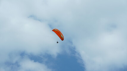 One paraglider flying through the blue sky with the white clouds