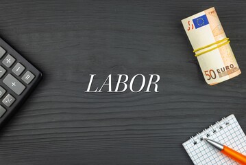 LABOR - word (text) and euro money on a wooden background, calculator, pen and notepad. Business concept (copy space).