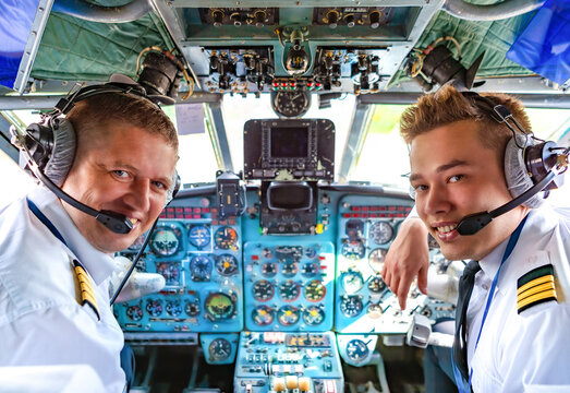 Happy pilots are smiling in the cockpit of an airplane. Greetings from the airline pilots.
