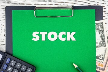 Obraz premium STOCK - word (text) dollar bills on green background, pencil, calculator and wooden white table. Business concept: buying, selling, commerce (copy space).