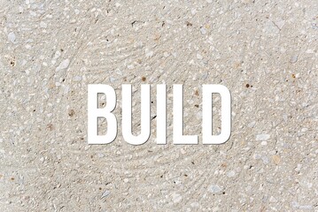 BUILD - word on concrete background. Cement floor, wall.
