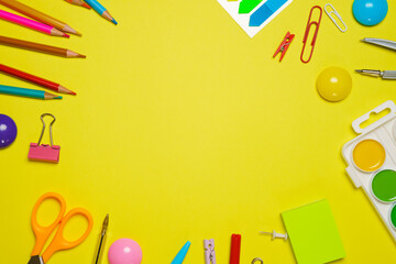 Frame with school supplies on a yellow background. Flat dip, top view