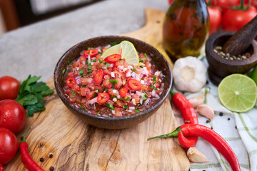 freshly made salsa dip sauce - chopped garlic, tomatoes and onion in wooden bowl