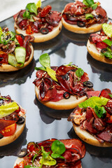 Appetizing bruschetta with ham on the buffet table. Beautiful service and catering. Business lunches and festive events. Close-up. Vertical.