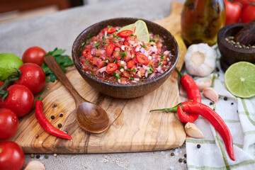 freshly made salsa dip sauce - chopped garlic, tomatoes and onion in wooden bowl