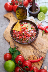 freshly made salsa dip sauce with nacho chips on wooden board