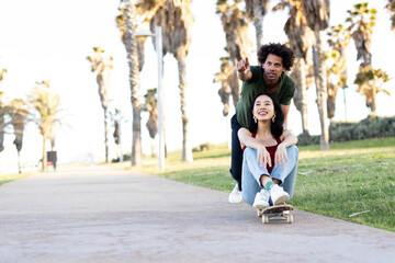 Fototapeta premium Beautiful couple having fun outdoors. Portrait of an excited young couple with skateboard.