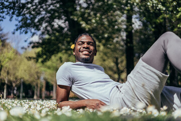 Naklejka na ściany i meble African american gay young man in a flowered park