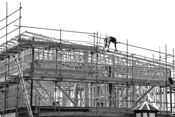 New home construction site with wooden frame and worker on the roof. Black and white photo.