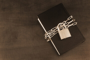 Banned information and secure concept, book with chain and padlock on wooden table. Copy space for...