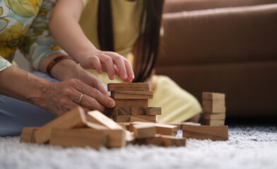 Cropped shot grandmother playing wooden blocks with her little grandchild in living room ,spending happy time on weekend together.