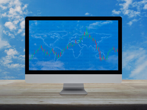 Trading graph of stock market with world map and graph on modern computer monitor screen on wooden table over blue sky, Business investment online concept, Elements of this image furnished by NASA