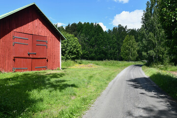 Red wooden hay barn in the countryside in summer