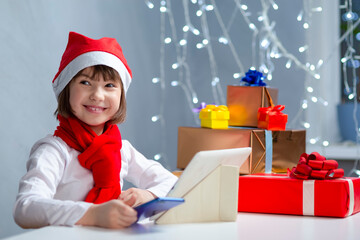Winsome Caucasian Child Kid Girl In Santa Hat Using Laptop for Online Gift Present Search While Using Video Calls