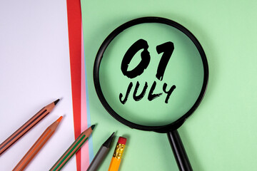 1 July. Black magnifying glass and office supplies on a green background