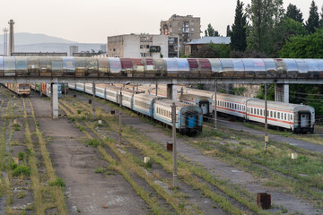 Abandoned passenger wagons on railroad tracks overgrown with grass under the bridge. Decommissioned...