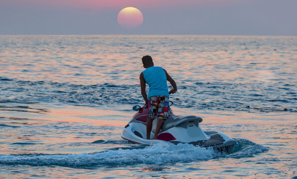 A man on jet ski jump on the wave at amazig sunset 