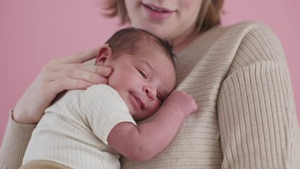 mum cuddling and bonding with her biracial newborn kid - mom and baby child together on pink background - Powered by Adobe