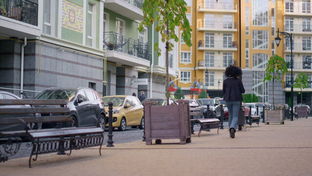 Rear woman walking city stroll empty street alone. Modern residential area. © stockbusters