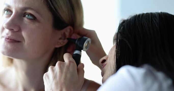 An otolaryngologist looks at a woman's ear close-up