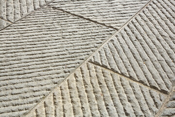New carved paving made with chiseled grey sandstone blocks in a italian pedestrian zone -...