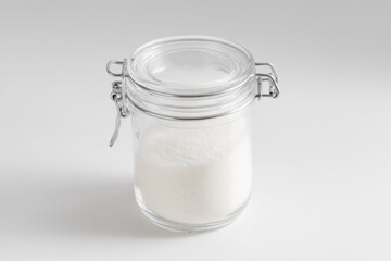 food storage, cooking and unhealthy eating concept - close up of white sugar glass jar on table