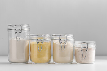food, culinary and storage concept - jars with different kinds of flour on white background