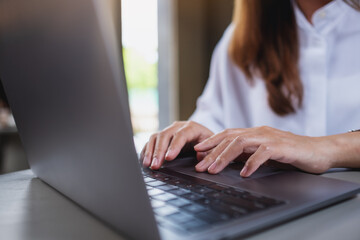 Closeup image of a woman working and typing on laptop computer keyboard in office