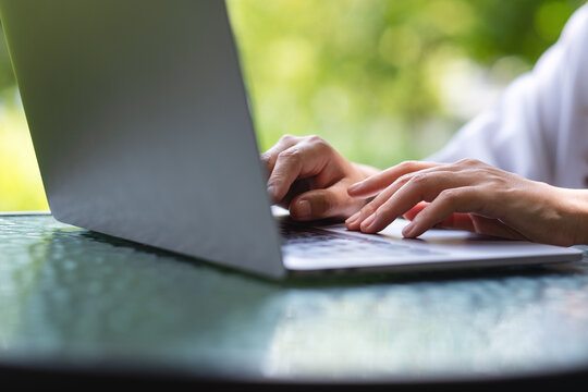 Closeup image of a woman working and typing on laptop computer keyboard in the outdoors