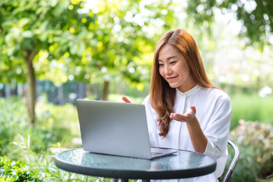 Portrait image of a young woman using laptop computer for video call and working online in the outdoors