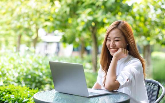 Portrait image of a young woman using and working on laptop computer in the outdoors