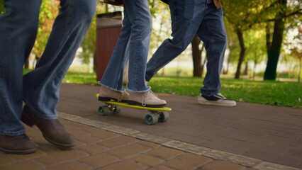 Fototapeta na wymiar Girl legs riding skateboarding in park closeup. Unknown parents support child.