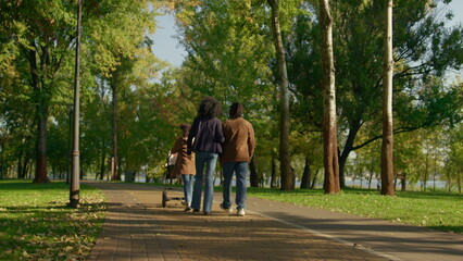 Fototapeta premium Casual parents walking autumn park rear view. Happy family weekend concept.
