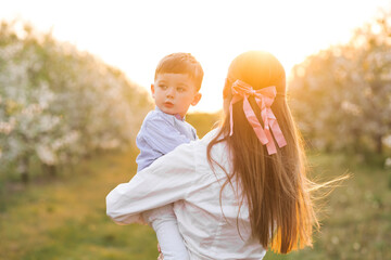 Happy mother and her baby boy walking on an apple farm in the spring