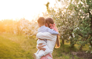 Fototapeta premium Sweet mother and her baby boy walking on an apple farm in the spring