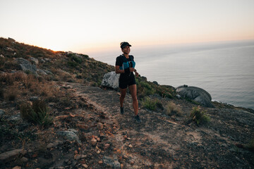 Fototapeta premium Trail runner exercising at sunset on mountain. Woman running on a hill.