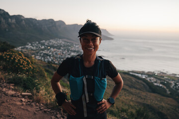 Fototapeta Woman hiker in sports wear looking at camera at sunset obraz