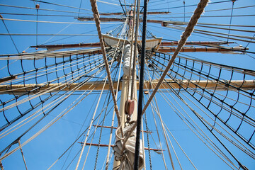 Fototapeta premium Ropes and the mast to control the sails, details of the device of the yacht, sailing ship equipment against the blue sky, horizontal view